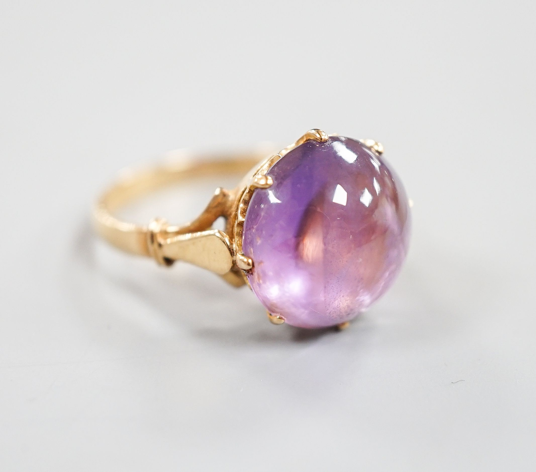 An early 20th century yellow metal and button shaped cabochon amethyst set ring, size R/S, gross weight 5.5 grams.